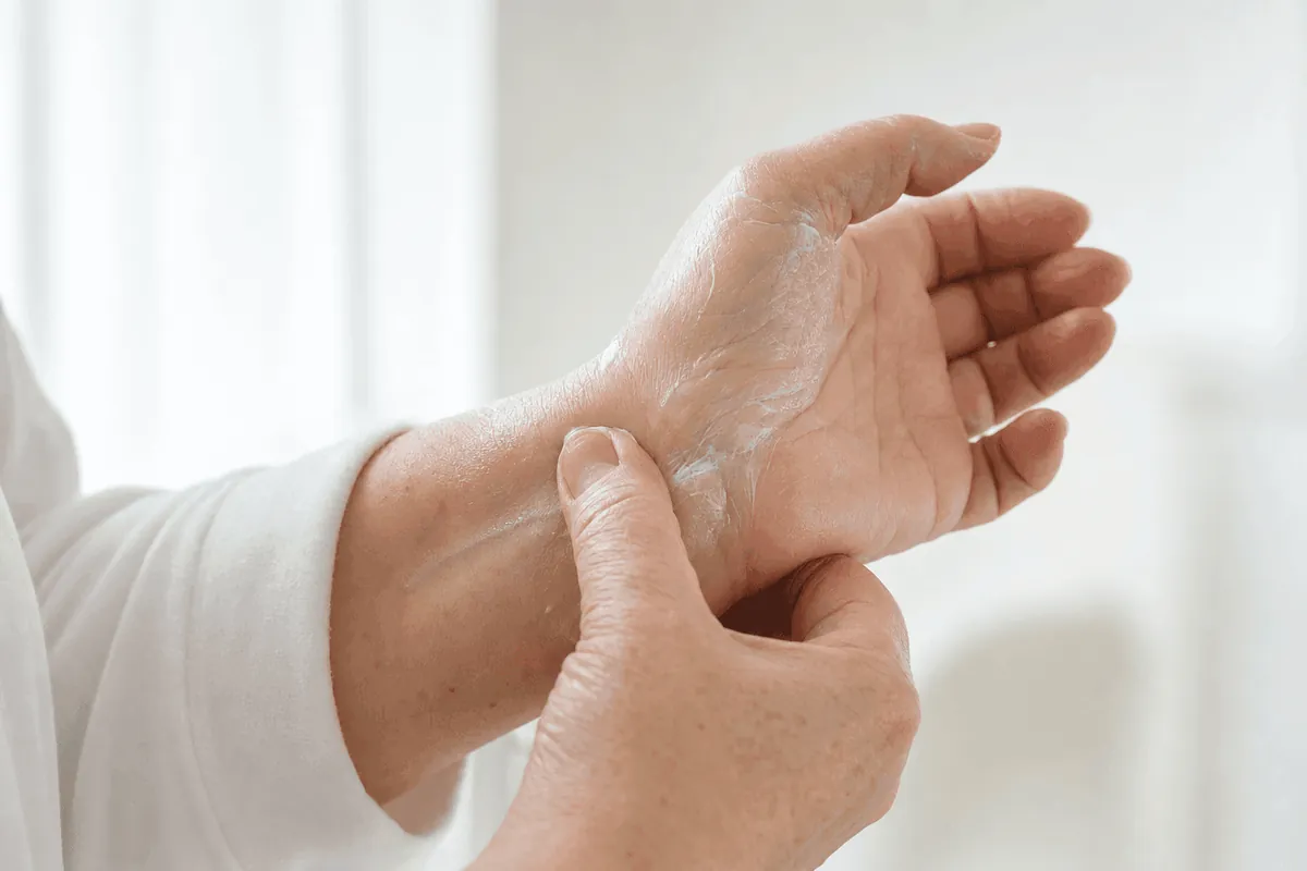 Mani che massaggiano la crema sul polso e sulla base del pollice